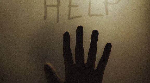 Angst Hand schreibt das Wort HELP an eine Glasscheibe