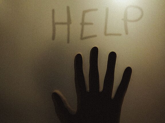 Hand schreibt das Wort HELP an eine Glasscheibe