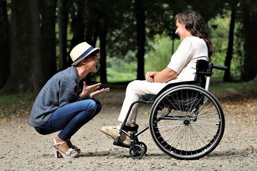 Betreuer kümmert sich um Rollstuhlfahrerin  